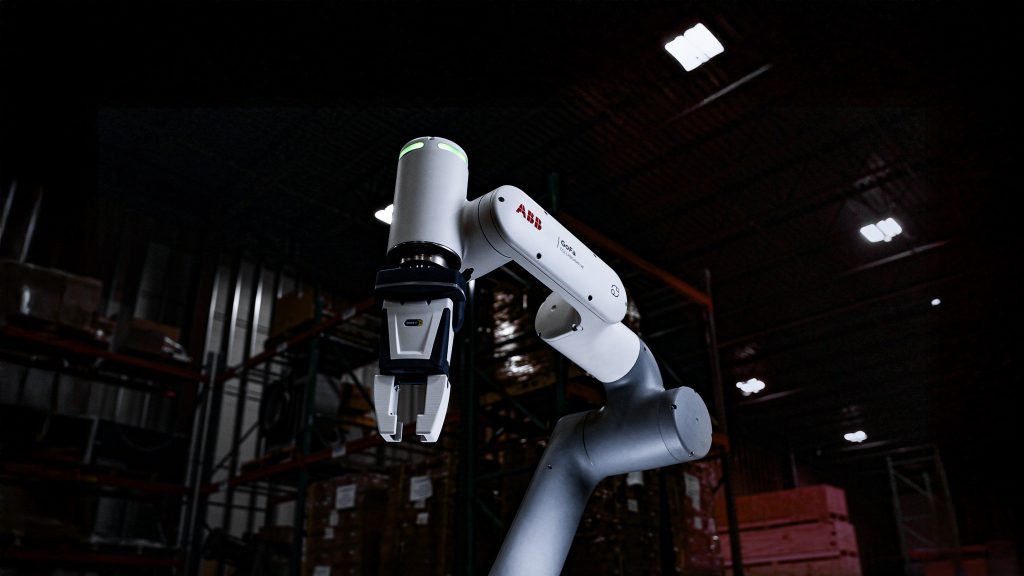 ABB GoFa collaborative robot arm in a dim warehouse, focusing on the end-effector/gripper area for picking tasks